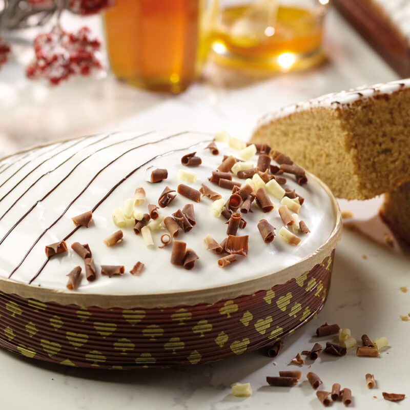 Winterkuchen in einer runden Papierbackform mit einer Fondant Schicht bedeckt und Schoko Späne garniert